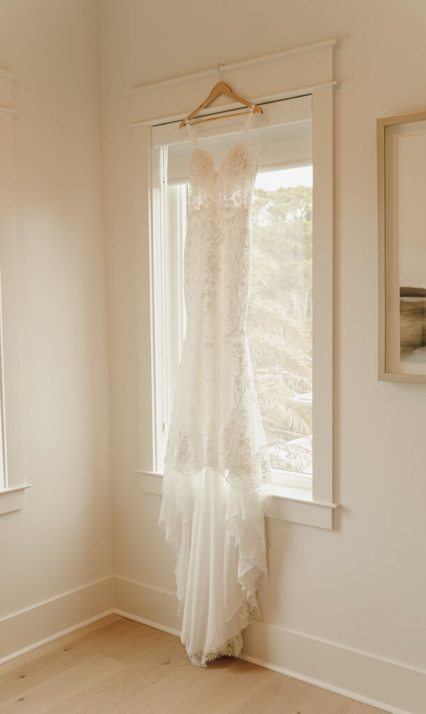 A wedding gown hanging in the window.