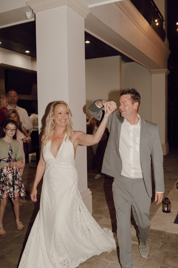 Bride and groom holding hands as they enter their wedding reception.