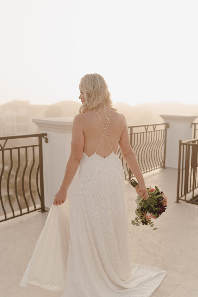 Bride holding her wedding dress out to the side with one hand while holding her bouquet in the other.