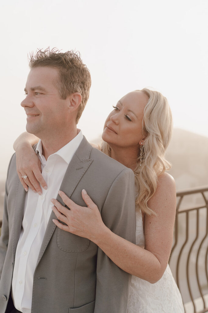 Bride hugging the groom from behind.