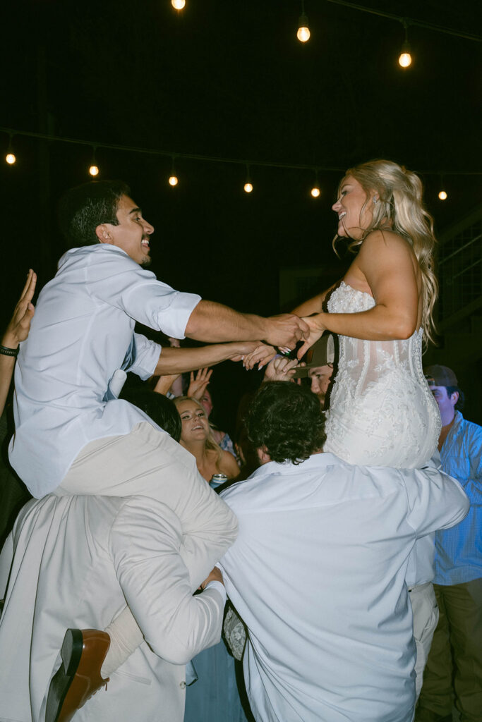 Bride and groom sitting on the shoulders of guests during the reception at Mount Pleasant Lodge.