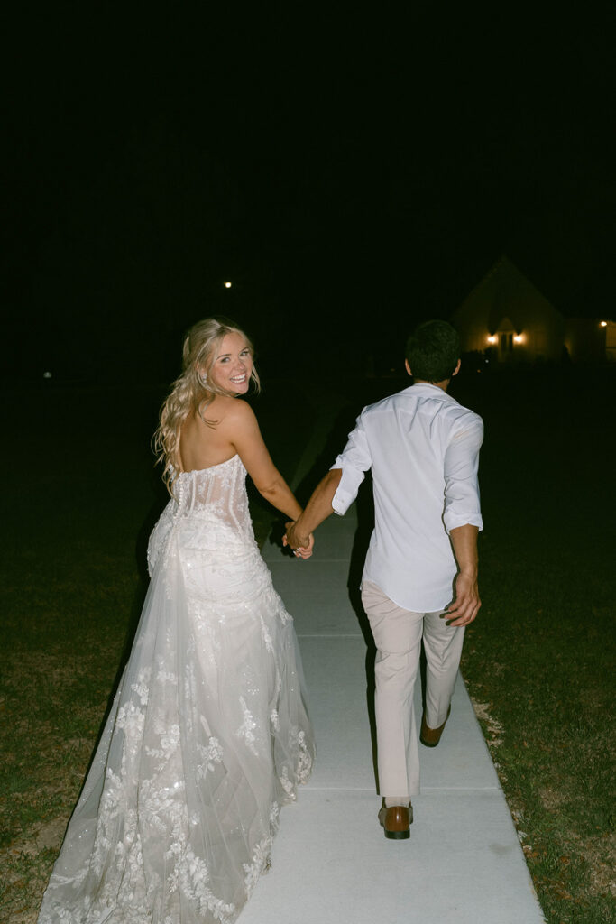 Bride and groom holding hands as they exit their wedding reception. 