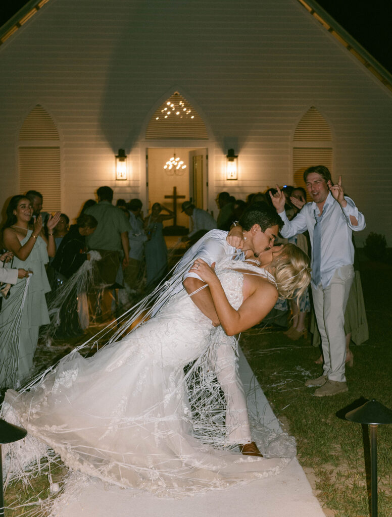 Candid wedding photos of the bride and groom kissing during their reception exit.