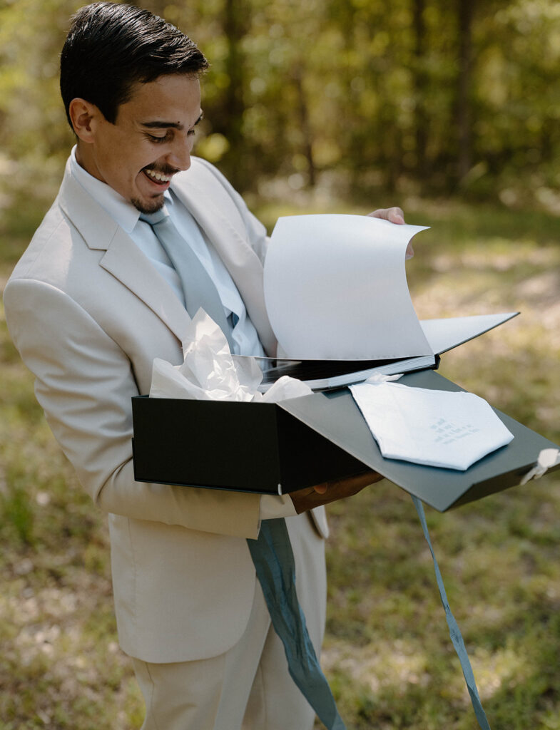 Groom smiling as he opens a gift. 