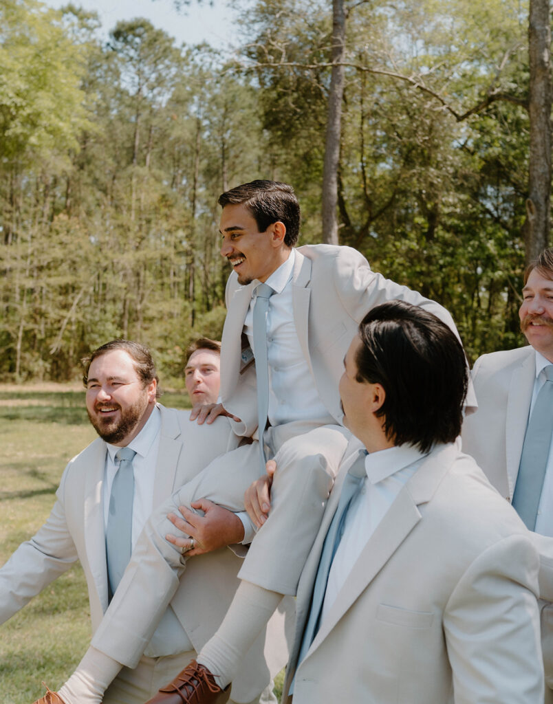 Groomsmen holding the groom in the air for candid wedding photos.