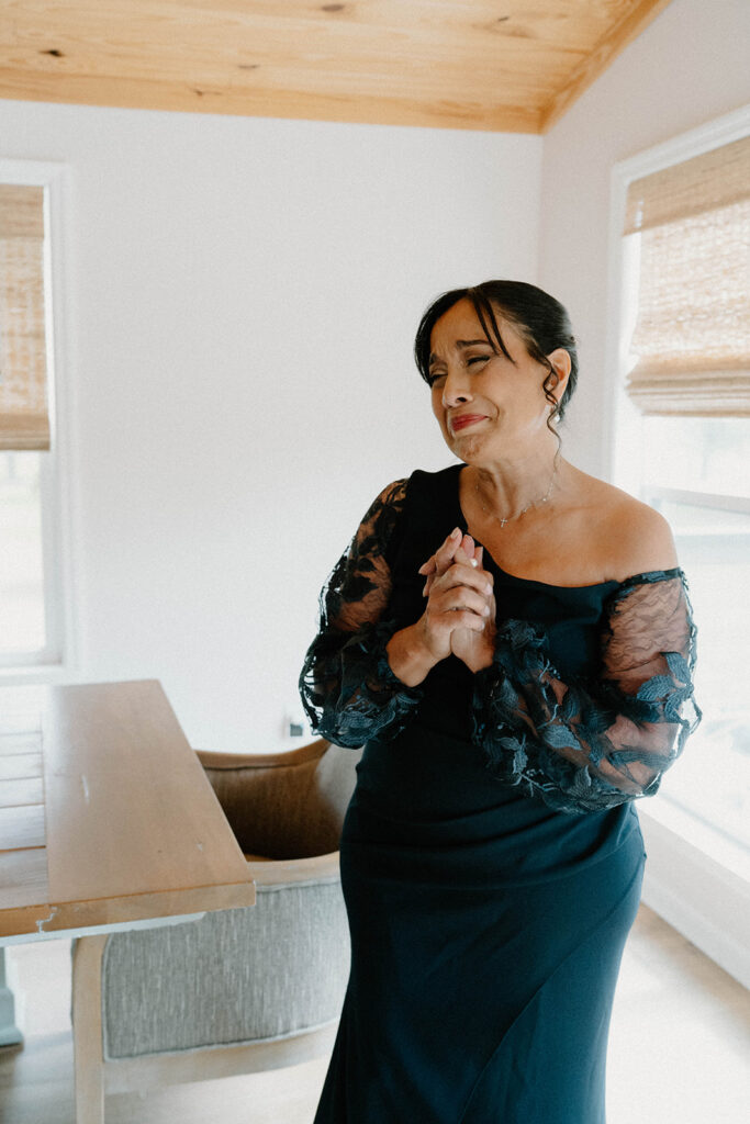 Mother in law of the bride holding back tears as she sees the bride.