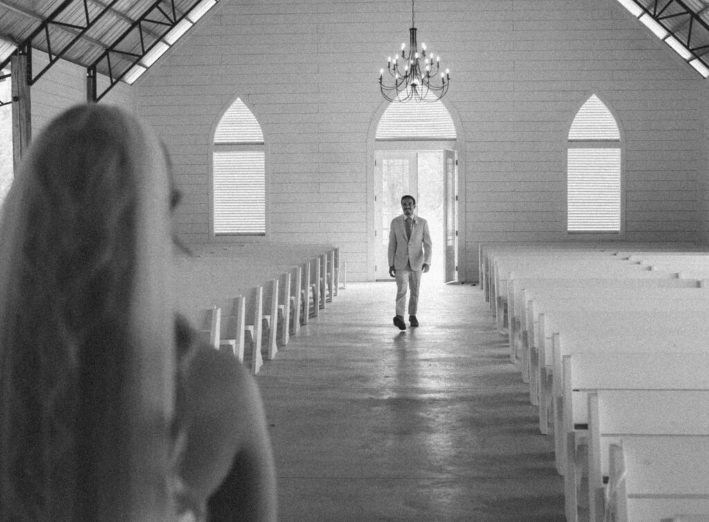 Groom walking towards his bride in the chapel at Mount Pleasant Lodge for candid wedding photos.