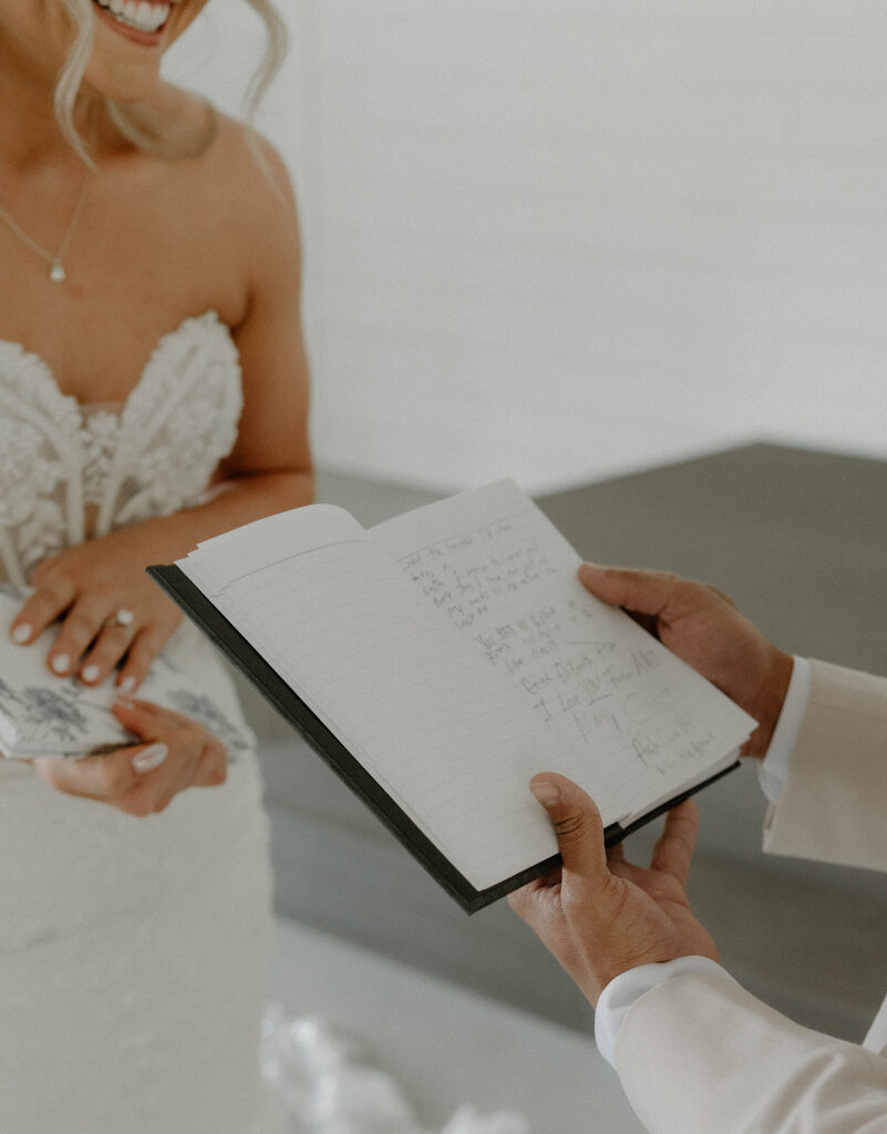 Groom reading his vows while the bride smiles.