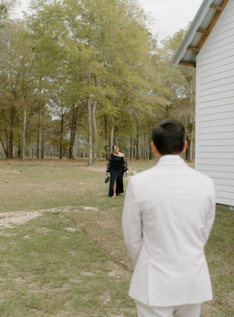 Candid wedding photos of the mother of the groom walking towards her son.