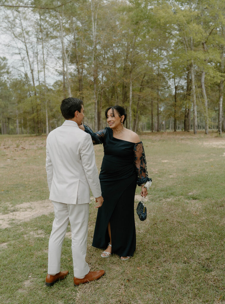Mother of the groom holding her son's cheek.