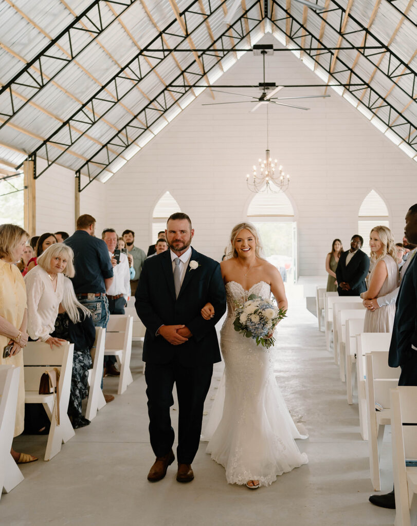 Father of the bride walking the bride down the aisle during the wedding ceremony.