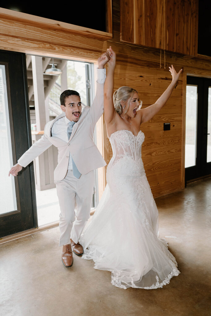 Candid wedding photos of bride and groom cheering as they enter the wedding reception.