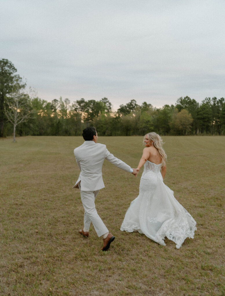 Bride and groom running in the field at Mount Pleasant Lodge for candid wedding photos.