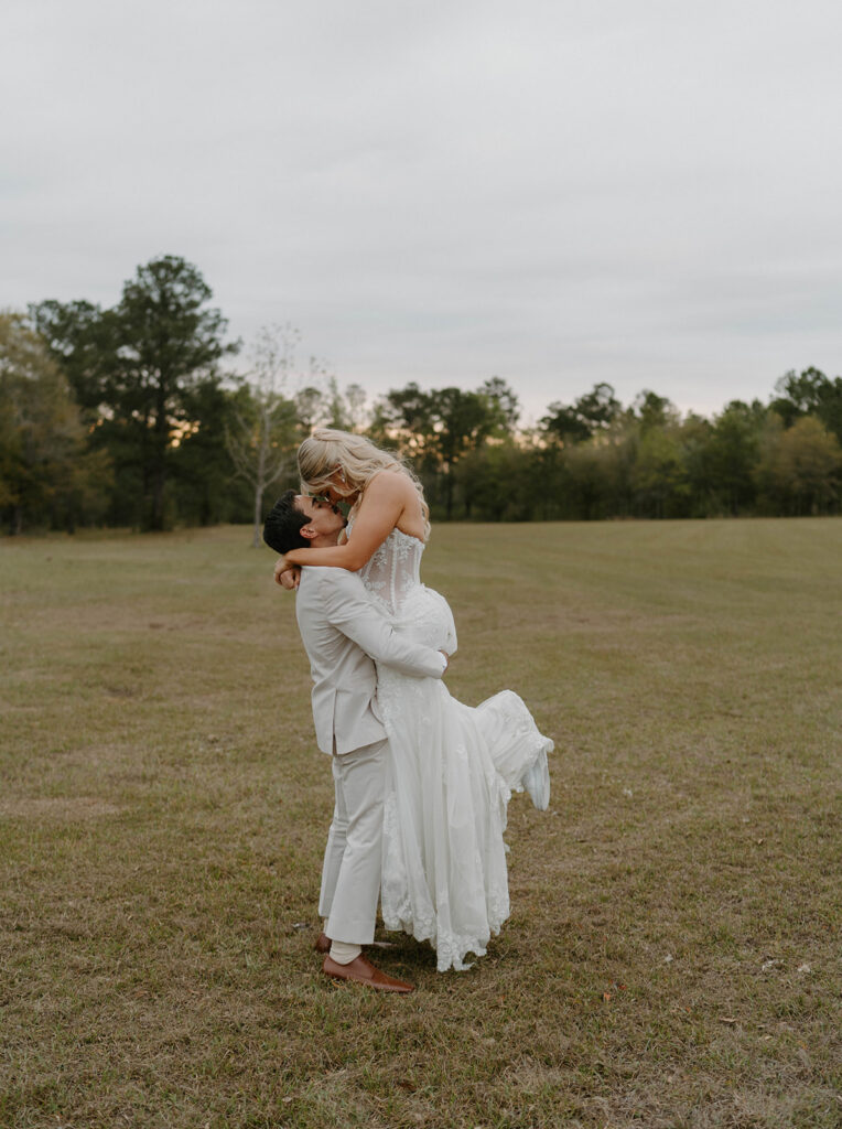 Groom lifting his bride in the air romantically. 