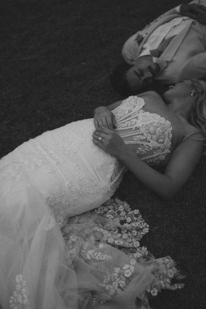 Candid wedding photos of bride and groom lying in the grass at Mount Pleasant Lodge.