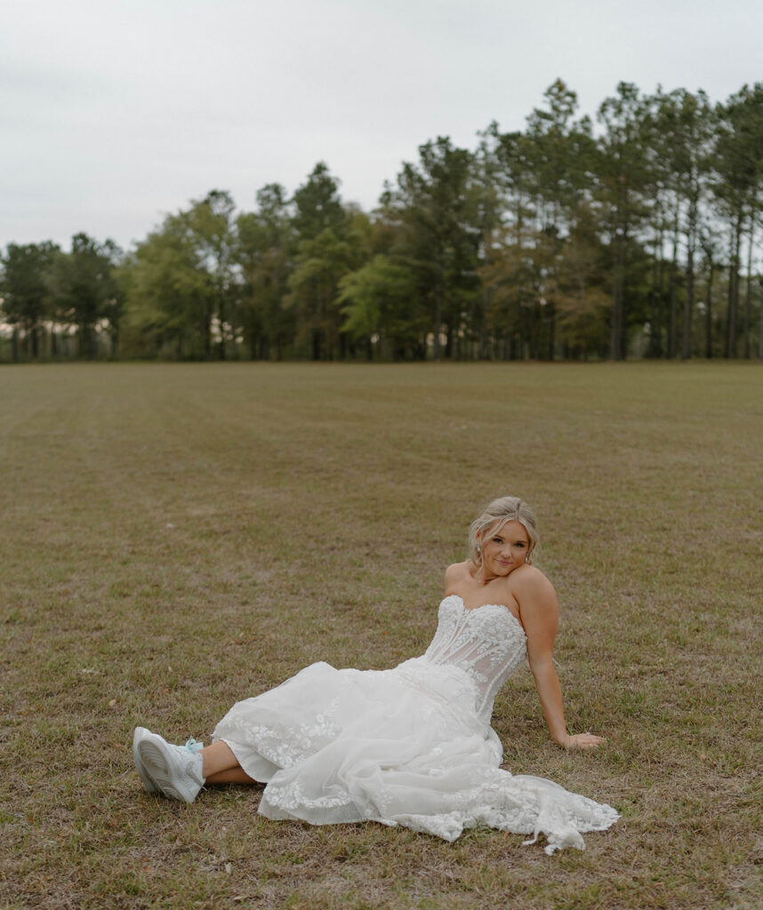 Bride sitting in the grass at Mount Pleasant Lodge for candid wedding photo poses.