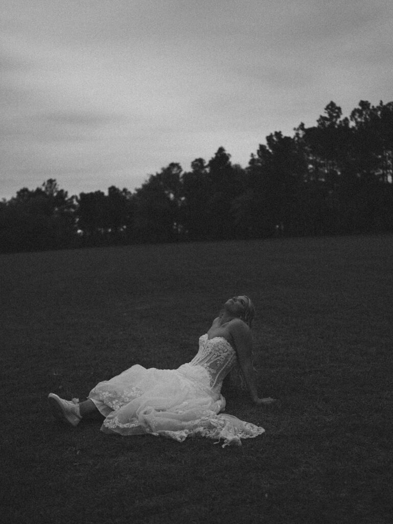 Candid wedding photos of the brie sitting in the grass in her wedding dress.