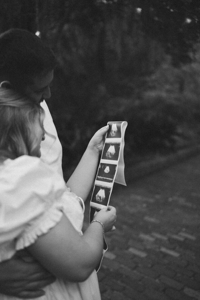 Couple looking at an ultrasound photo strip together for pregnancy announcement photos.