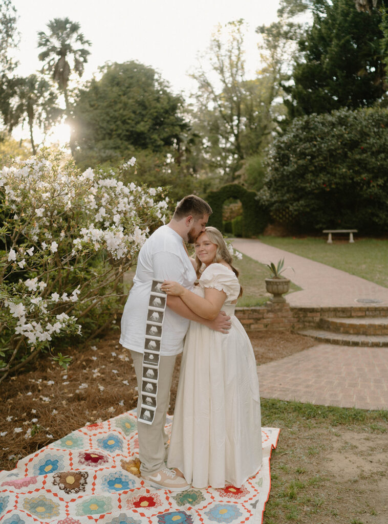 Couple hugging while holding an ultrasound photo strip for pregnancy announcement photos. 