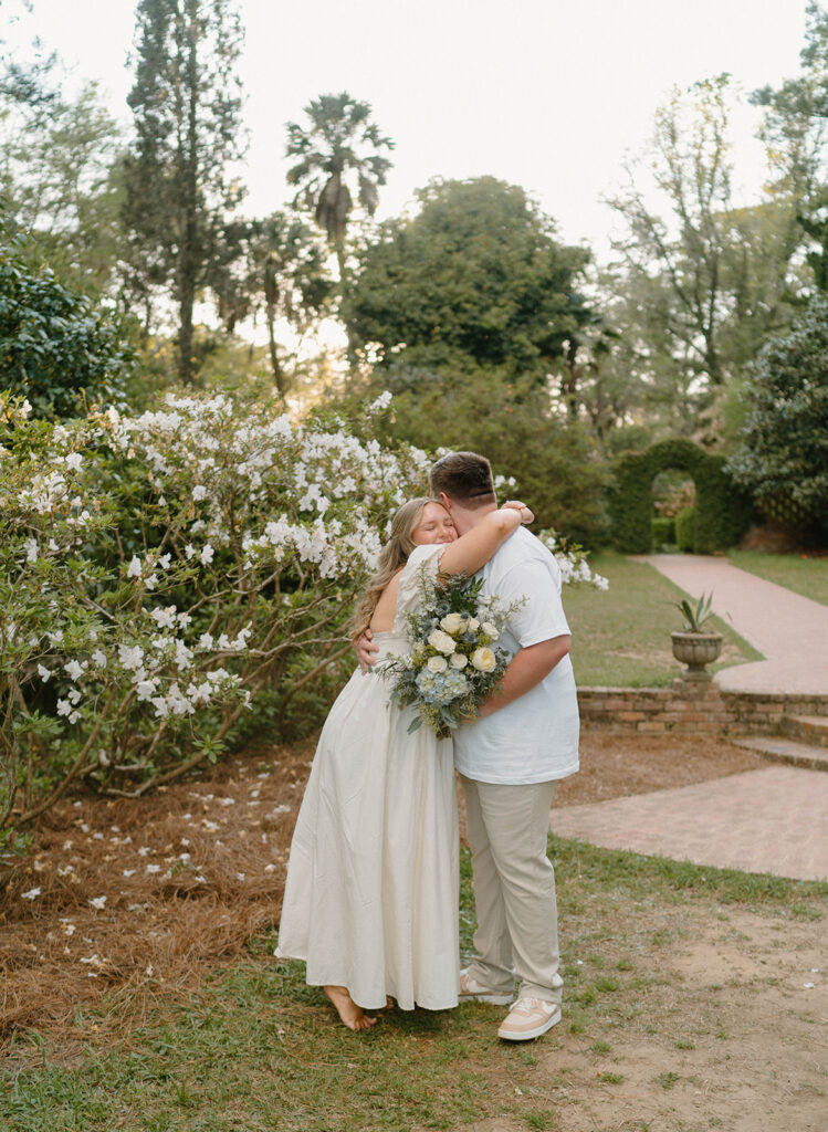 Couple hugging while holding a blue bouquet.