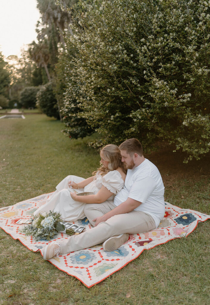 Couple sitting on a colorful baby blanket for pregnancy announcement photos.