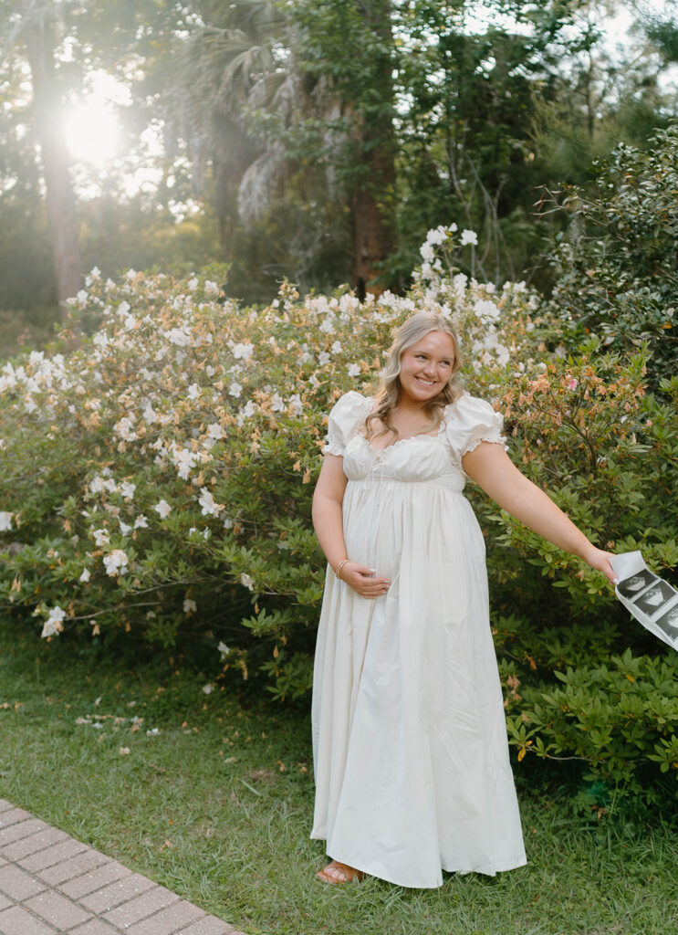 Woman holding her pregnant belly by flowers for Alfred B Maclay Gardens State Park photos.