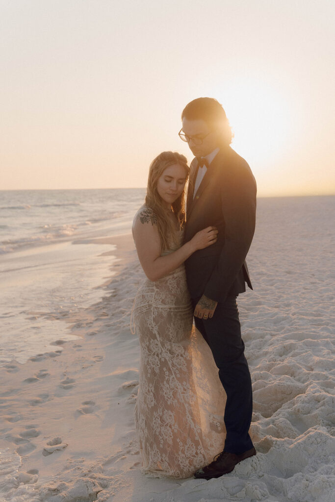 Bride and groom looking at the sand during sunset. 
