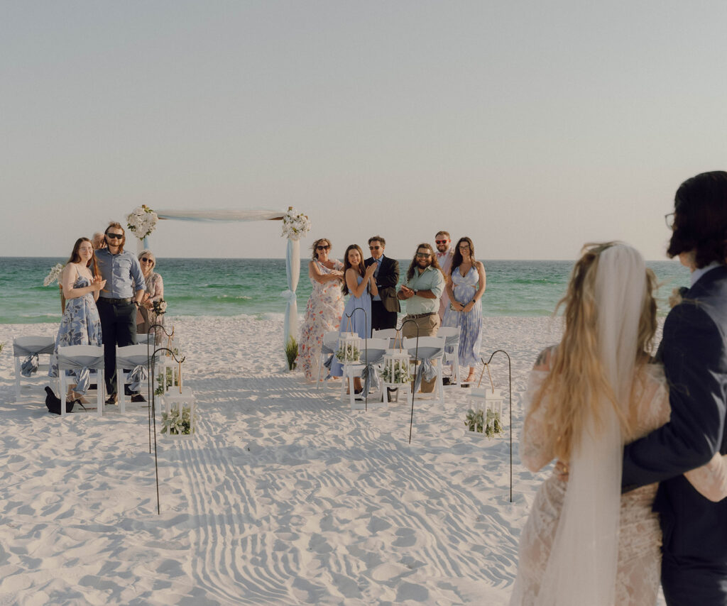 Wedding guests cheering as the bride and groom walking down the aisle. 
