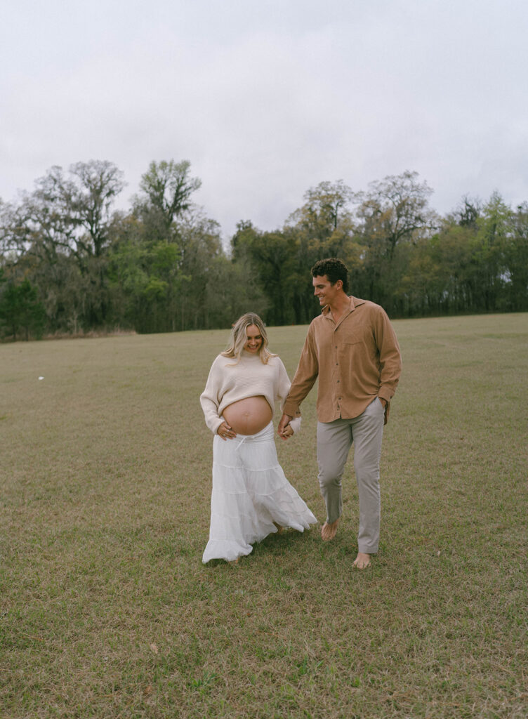 A couple walking hand in hand in an open field in Tallahassee.