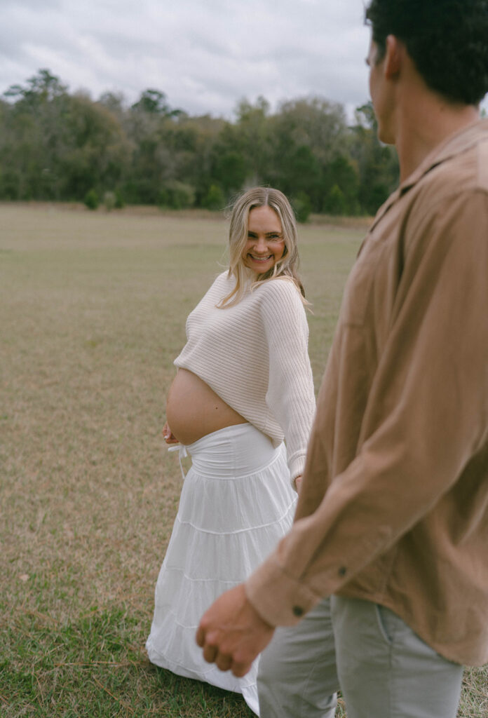 A pregnant woman smiling really big as she looks at her husband.
