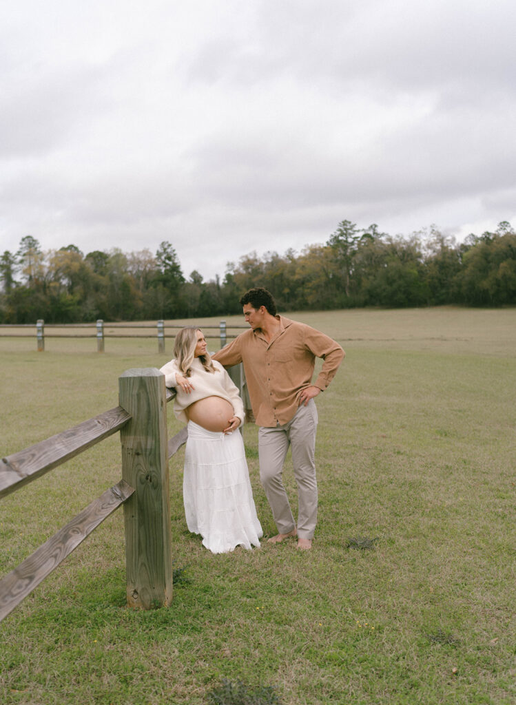 A couple leaning on a fence in a field in Tallahassee.