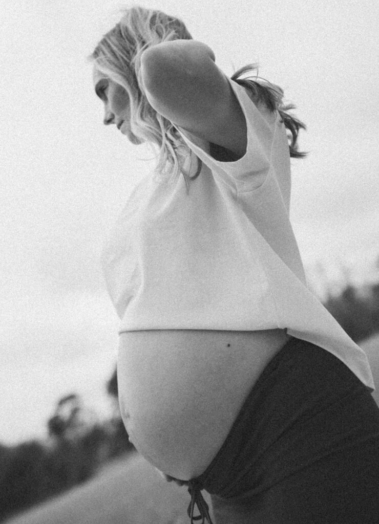 A woman holding her belly as she looks off into the distance.