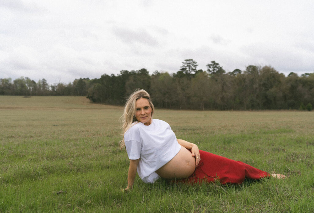 A woman in a white shirt and long red skirt lying in the grass of an open field at J.R. Alford Greenway.