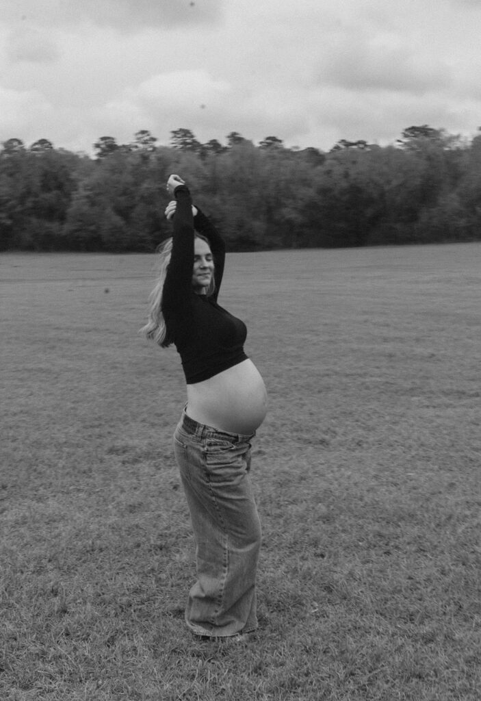 A pregnant woman with her hands in the air during maternity photos.