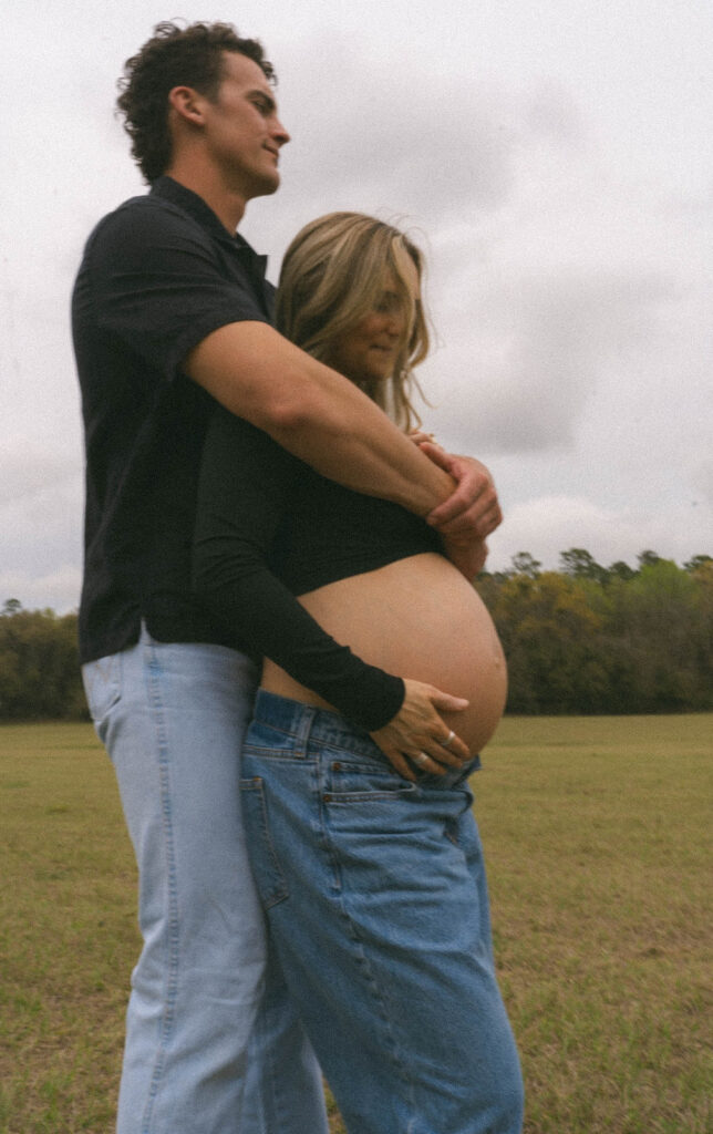 A man with his arms around his pregnant wife.