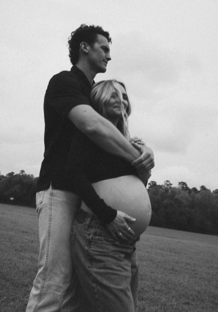 A man with his arms wrapped around his pregnant wife for maternity photos.