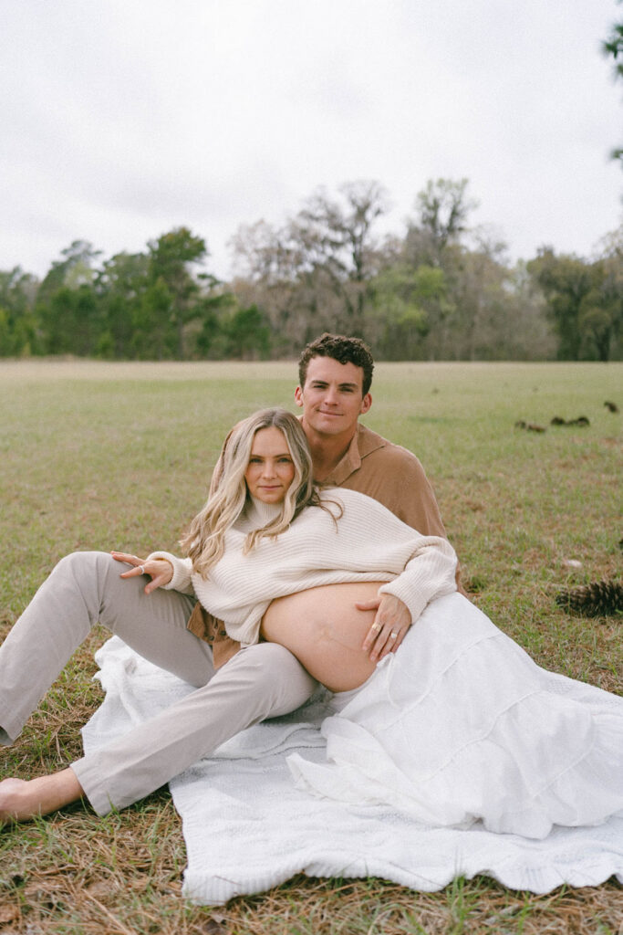 A couple sitting on a blanket at the J.R. Alford Greenway for maternity photos.