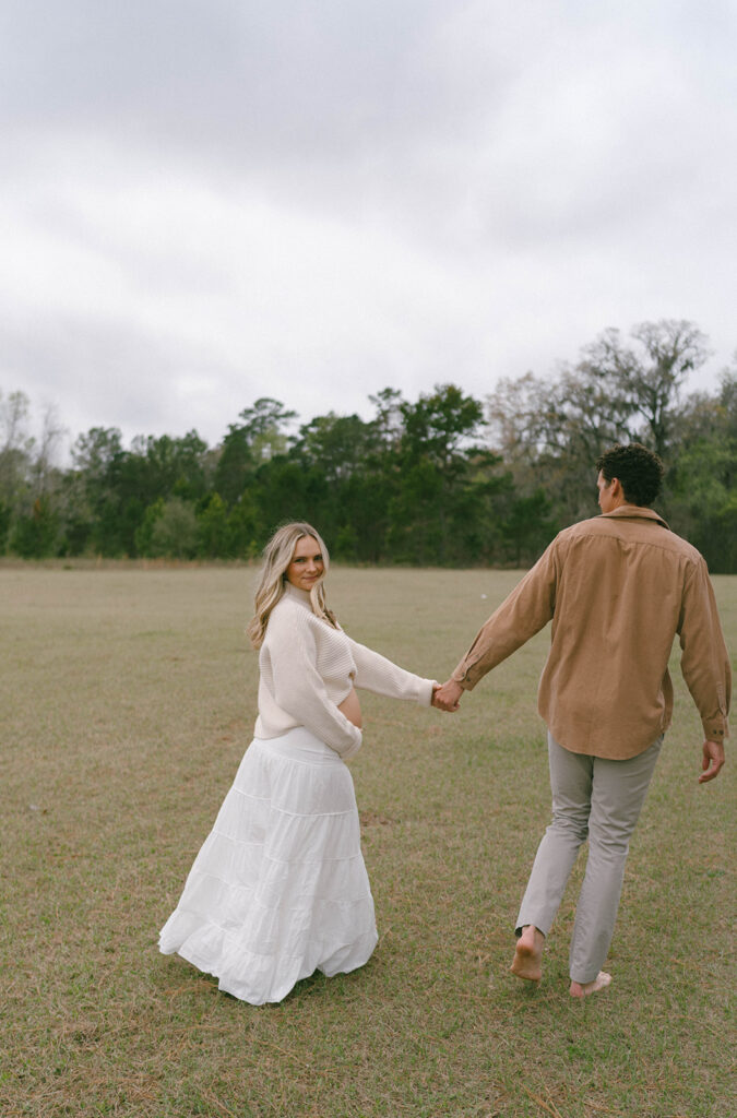 A woman looking back while she holds her husband's hand and walks away.