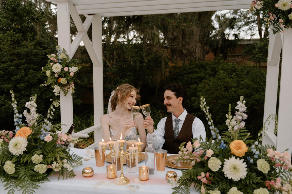 Bride and groom toasting at their sweet heart table at their Avera-Clarke House wedding,