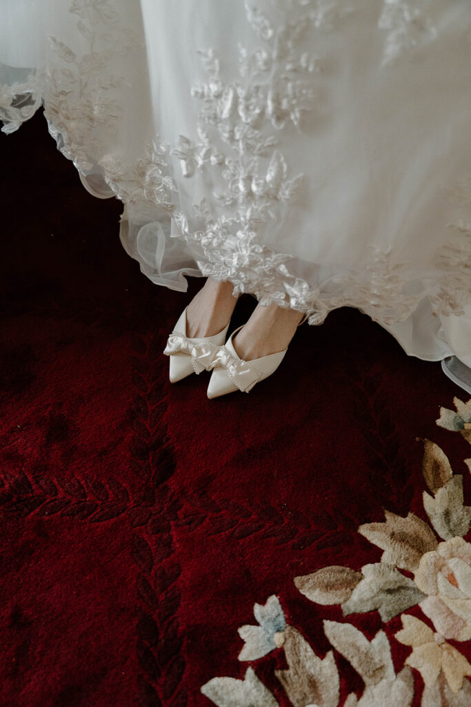 White satin bridal heels on a velvet red carpet at The Avera-Clarke House.