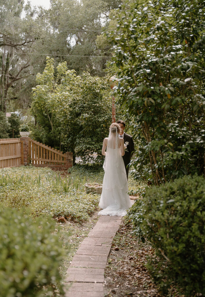 Bride and groom having their first look in the garden of The Avera-Clarke House.