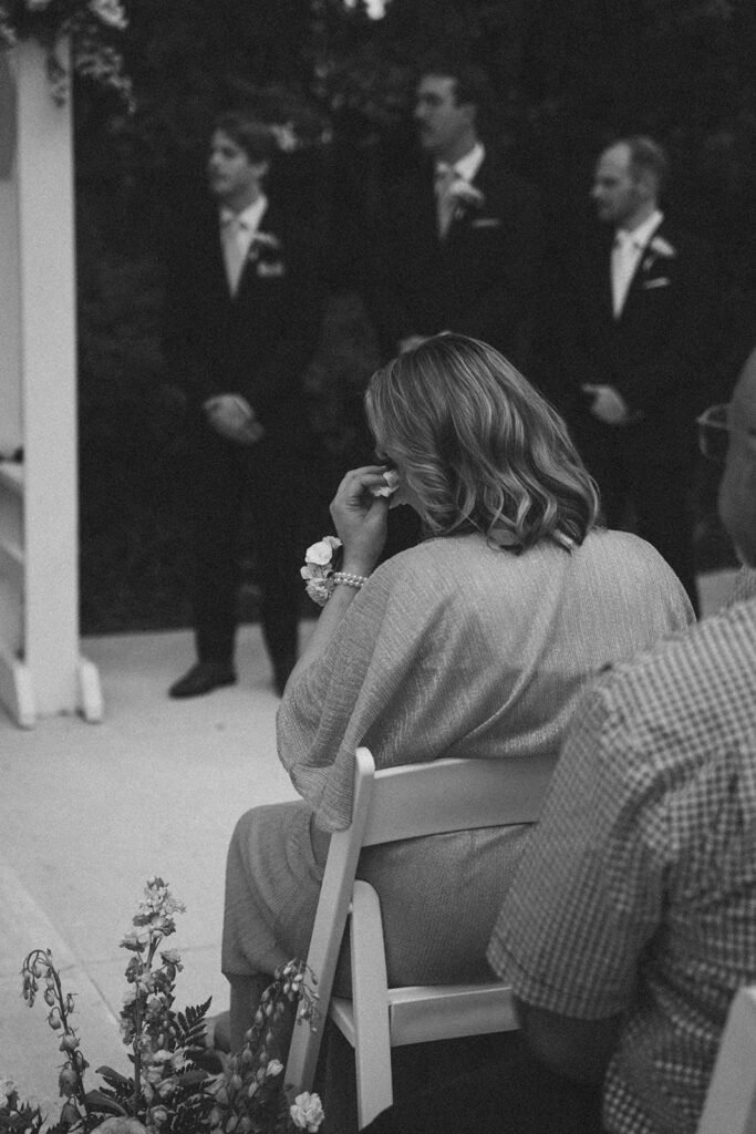 Mother of the bride wiping her tears with a tissue during the ceremony. 