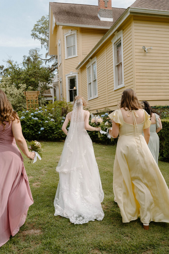 Bride and bridesmaids walking towards The Avera-Clarke House.