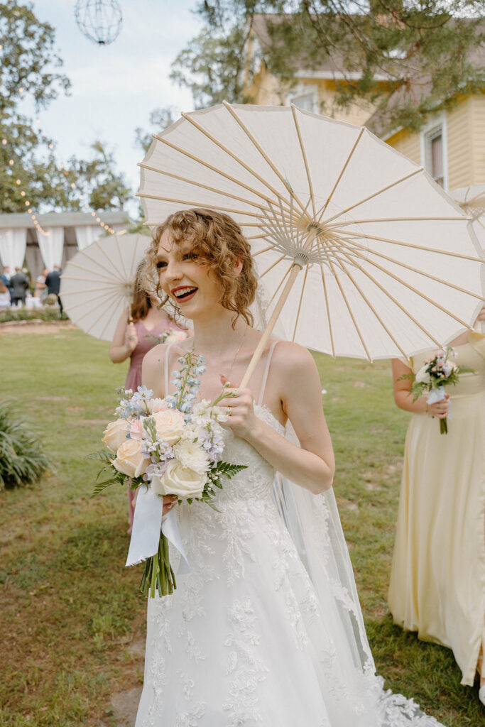 Bride smiling while holding a parasol.