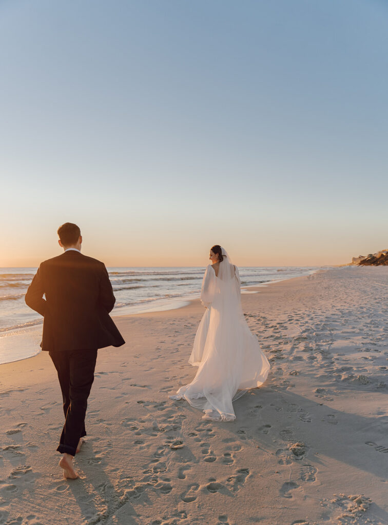 Groom running after his bride on along the beach.