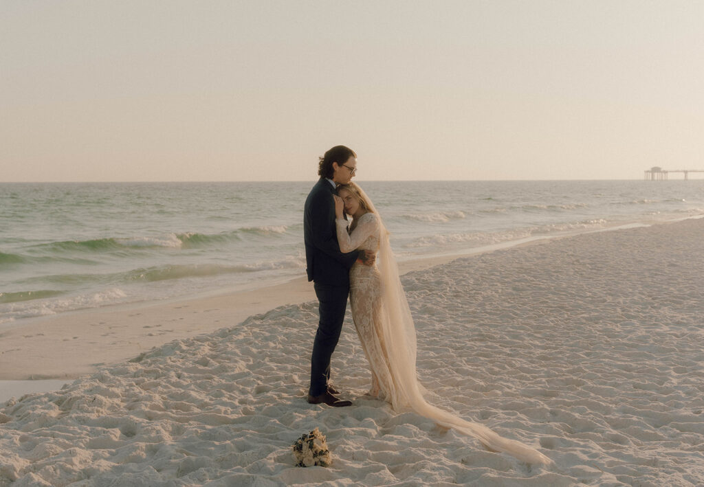 Bride leading on her husband by the ocean.