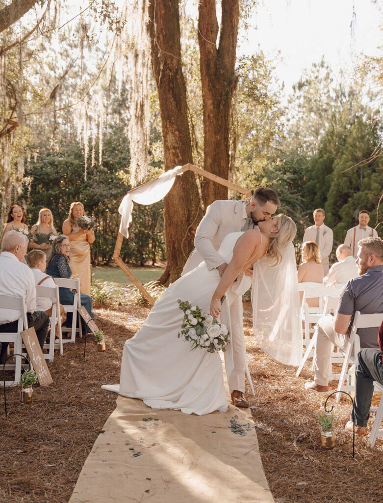 Bride and groom kissing in the aisle at The Homestead Barn, their Tallahassee wedding venue.