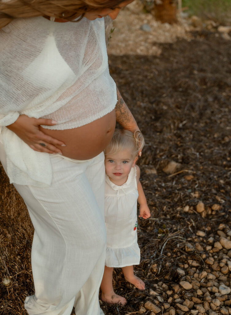 Pregnant mother holding her belly and toddler.