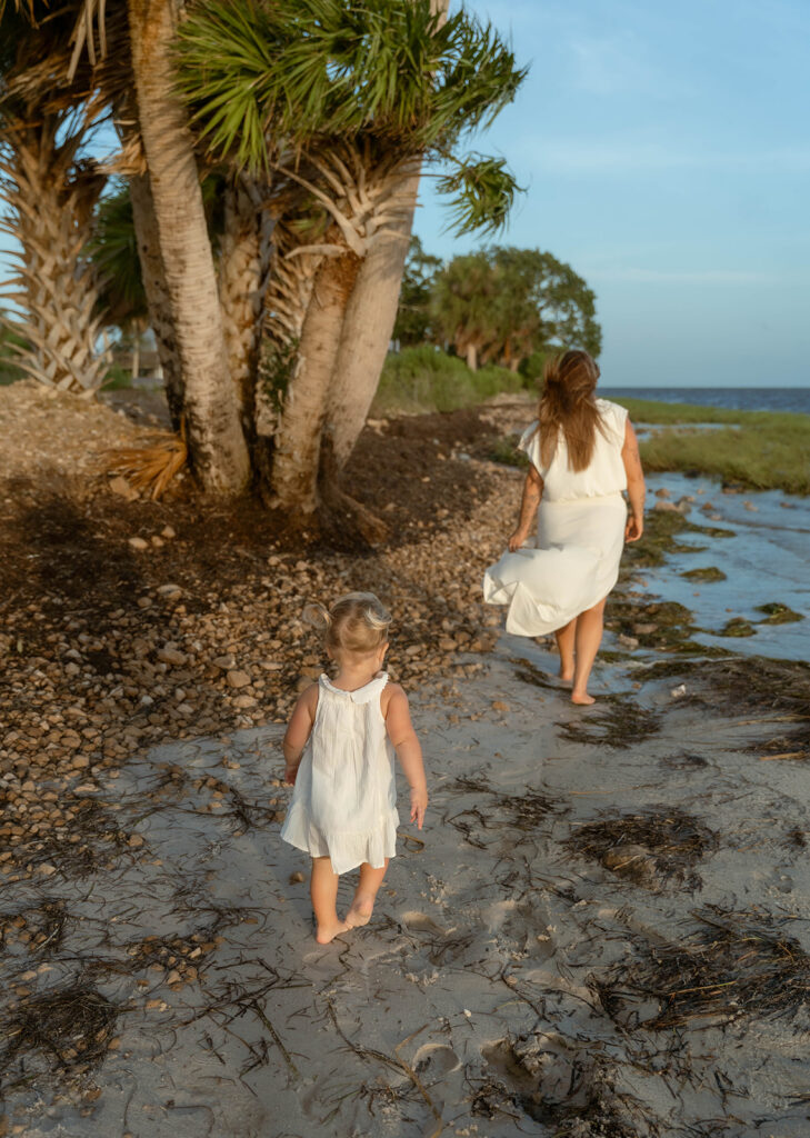Toddler walking behind her mother for family maternity photos in Florida.