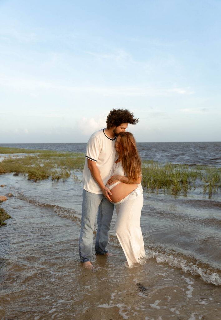 Man holding and kissing his pregnant wife.
